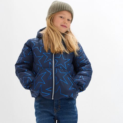 Gesteppte blaue Jacke, Jeans und eine kuschelige grüne Mütze.