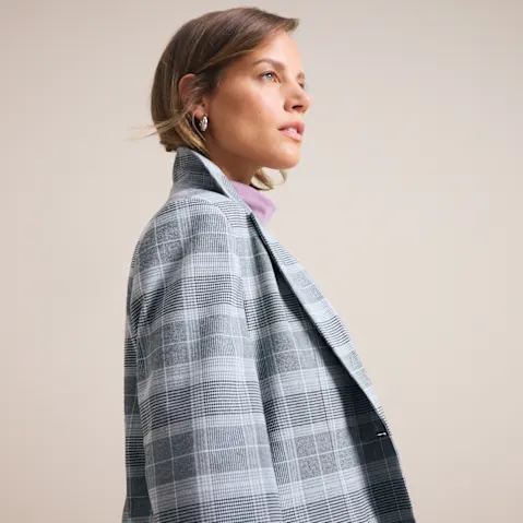 Eleganter grauer Karoblazer über einem pinken Rollkragenpullover, ein stilvolles Outfit.