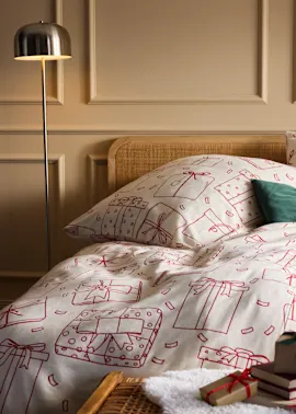 Neben dem Bett steht eine silberne Lampe.