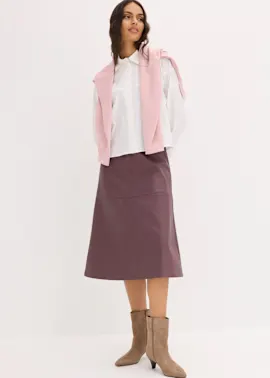 Weißes Hemd, rosa Pullover über den Schultern, pflaumenfarbener Rock und beige Stiefeletten.