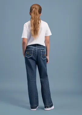 Ein Mädchen von hinten in einem weißen T-Shirt und blauen Jeans mit weißen Nähten.