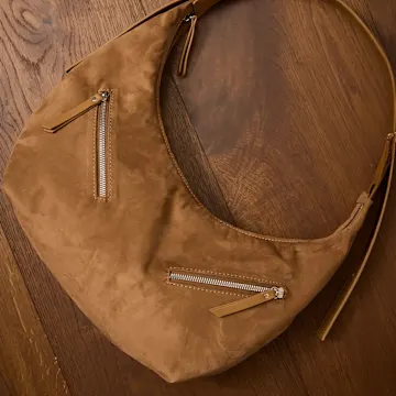 Elegante braune Ledertasche mit Reißverschlüssen auf Holzuntergrund.
