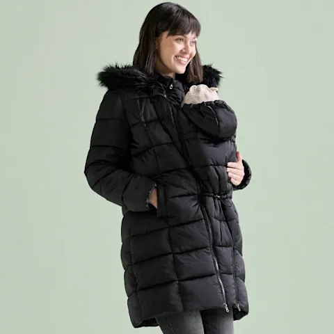 Warmer schwarzer Mantel über beiger Fleecejacke und dunkler Hose.