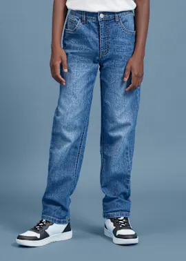 Blaue Jeans, ein weißes T-Shirt und schwarz-weiße Sneaker bilden das Outfit.