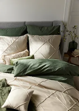 Beige Kissen liegen auf dem Bett.