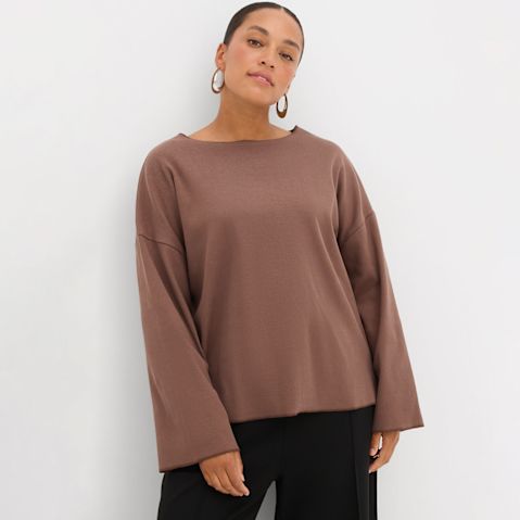 Braunes Langarmshirt mit weiten Ärmeln, kombiniert mit schwarzer Hose.