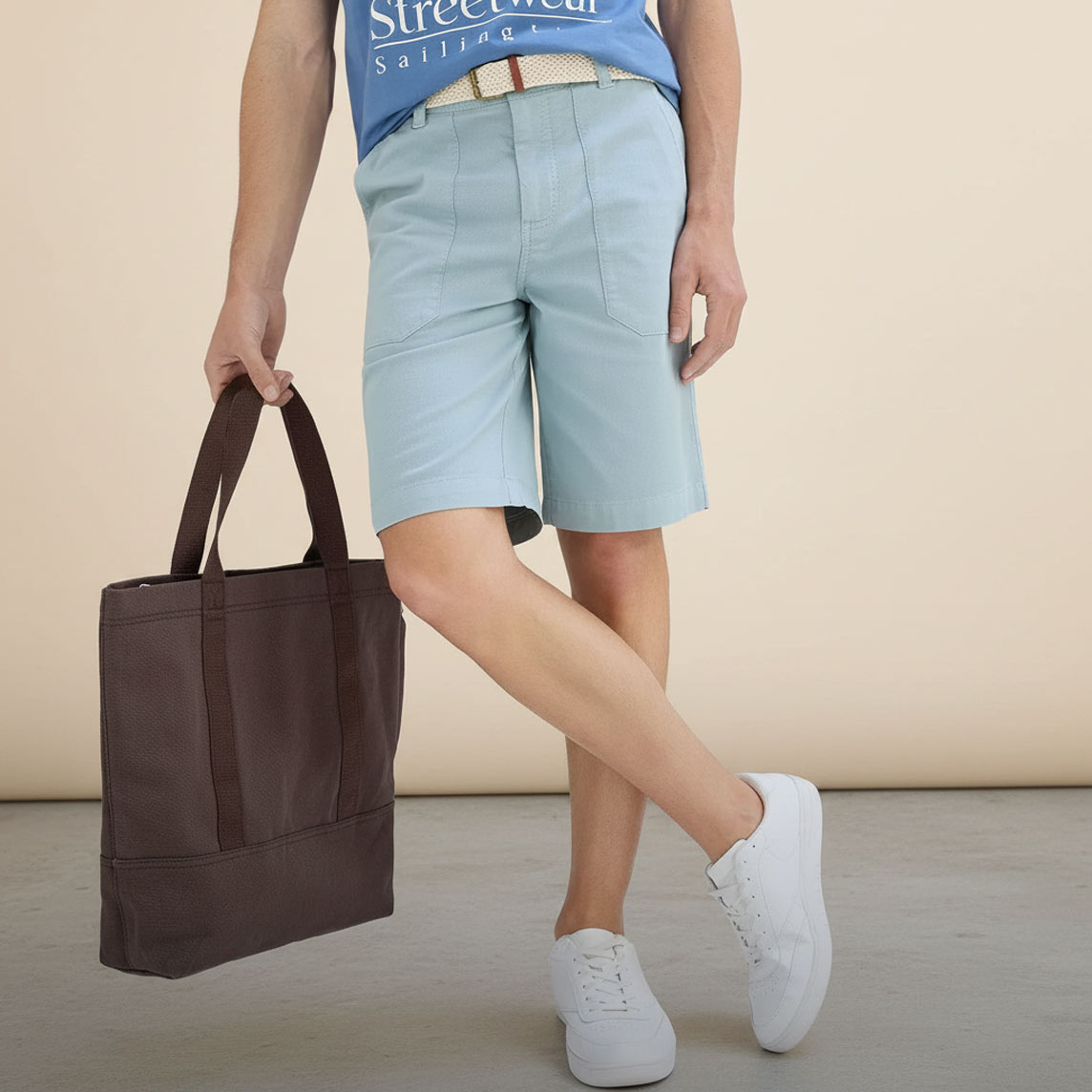 Blaues T-Shirt, hellblaue Shorts, weißer Gürtel und weiße Sneaker bilden ein frisches Sommer-Outfit.