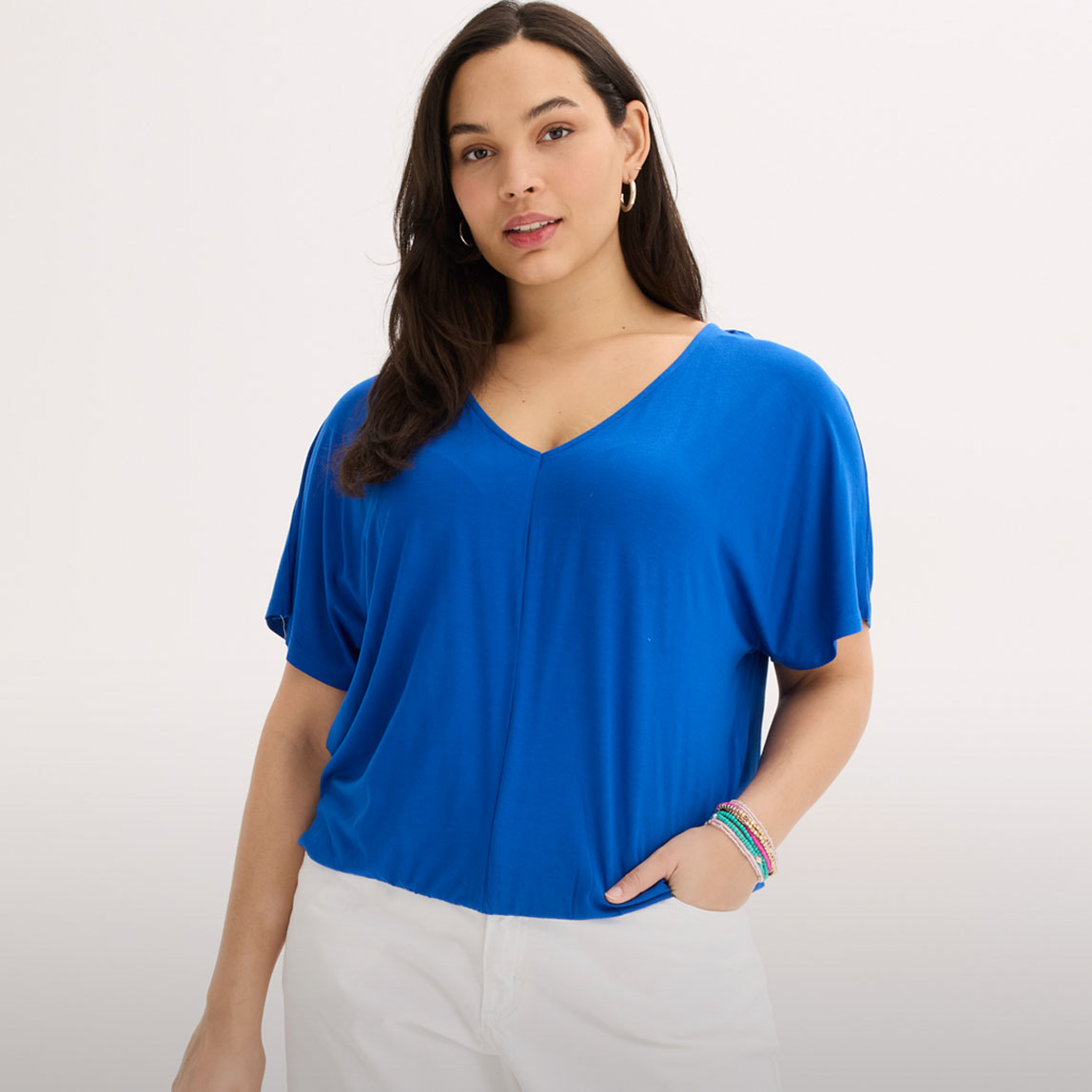 Blaues Oversize-Shirt mit V-Ausschnitt und weiße Hose.