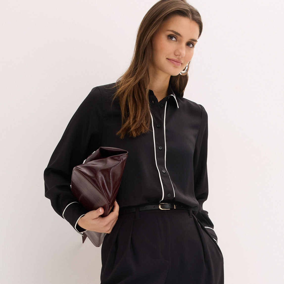 Schwarze Hemdbluse mit weißem Kragen, kombiniert mit schwarzer Hose.