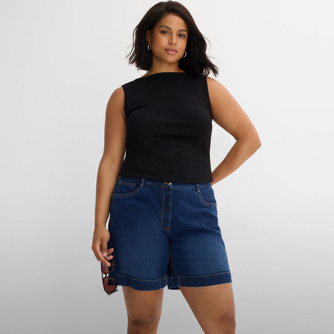 Schwarzes Top und lässige blaue Jeans-Shorts.