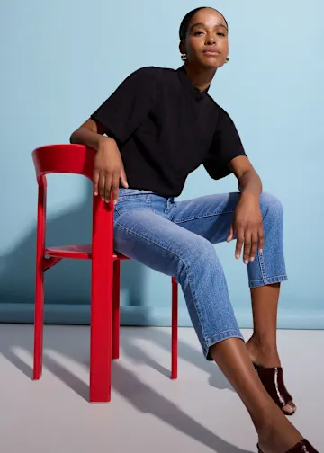 Outfit mit schwarzem Oberteil, blauen Jeans und glänzenden Mules.