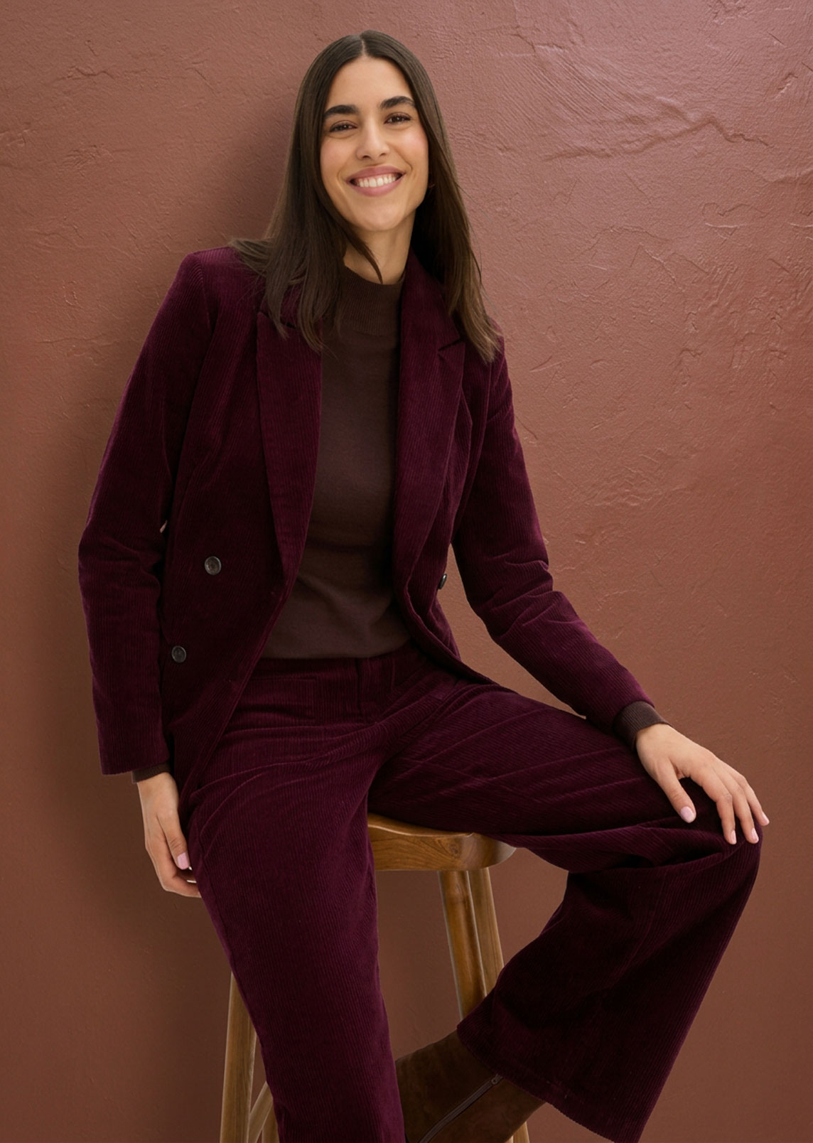 Samtener Blazer und Hose in tiefem Bordeauxrot, kombiniert mit braunem Oberteil.