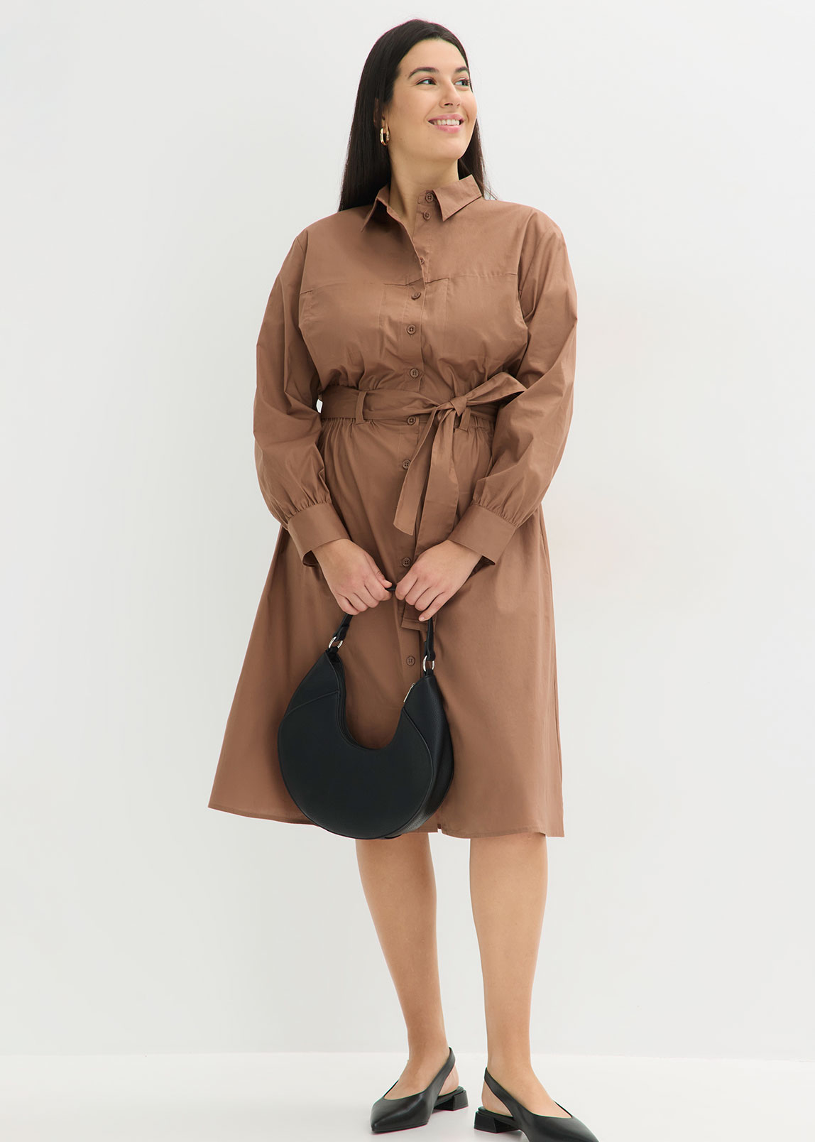 Braunes Hemdblusenkleid mit Bindegürtel, kombiniert mit schwarzer Handtasche.
