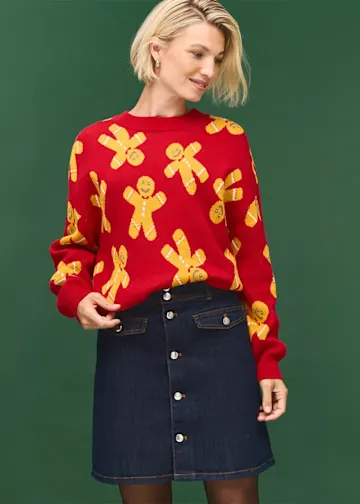 Roter Pullover mit Lebkuchenmännern und dunkler Jeansrock mit auffälliger Knopfleiste.