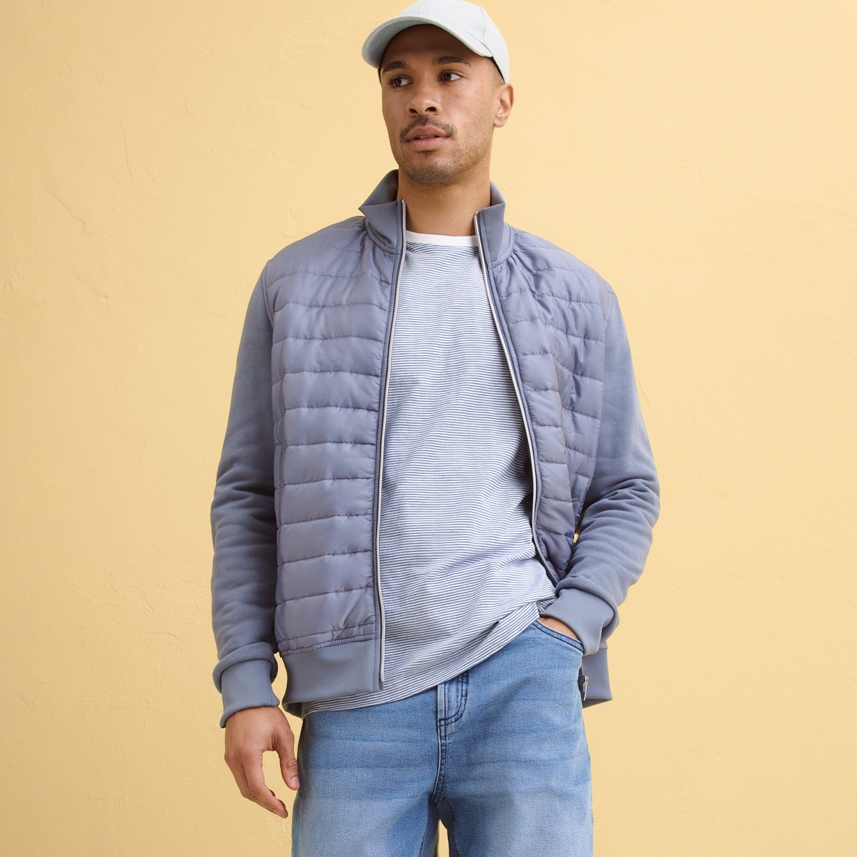 Grau-Blaue Steppjacke über hellgrauem Shirt, blaue Jeans.