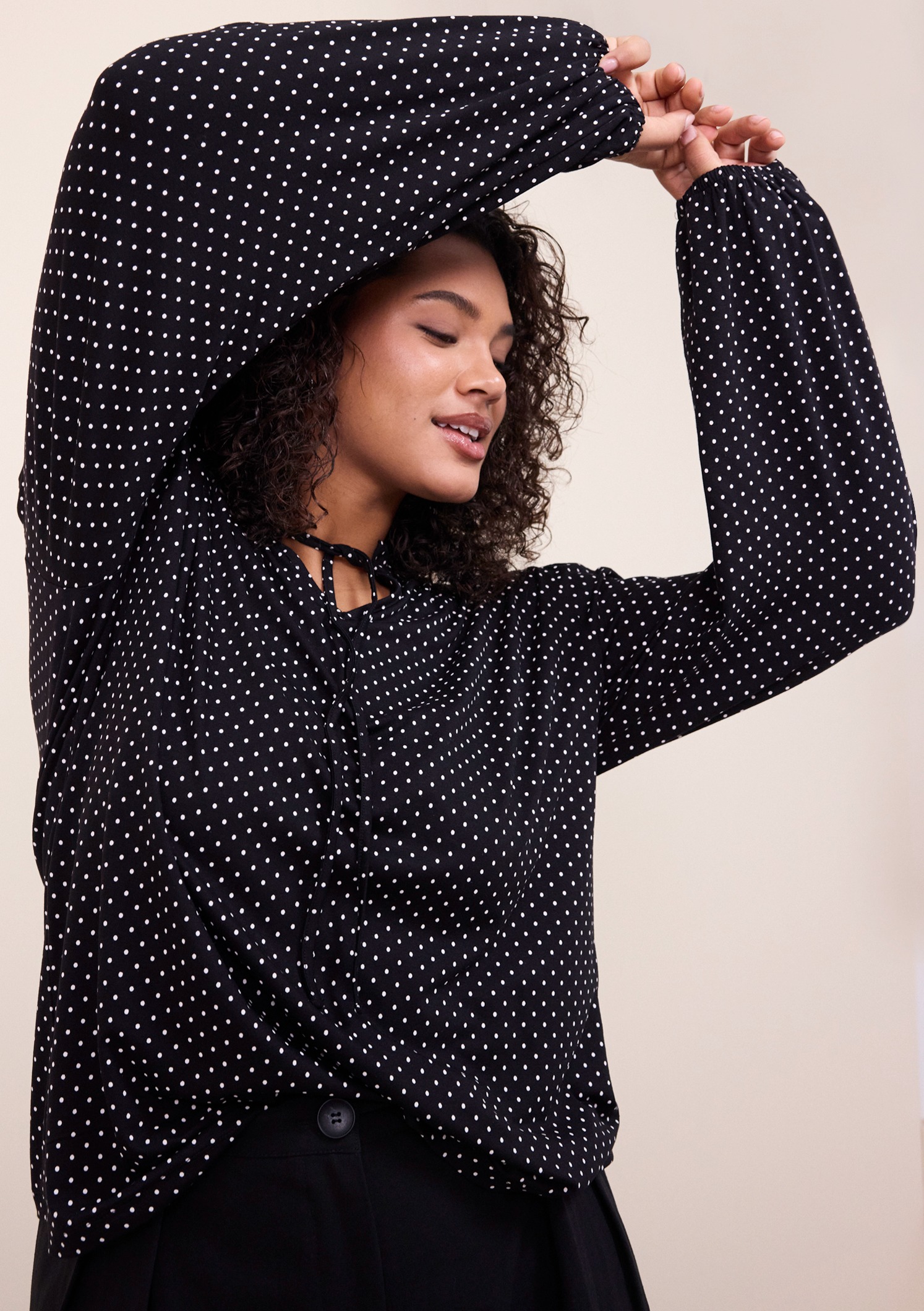 Schwarze Bluse mit weißen Punkten und langen Ärmeln. 