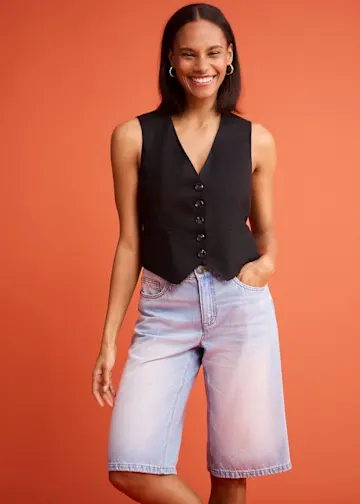 Schwarze Weste mit Knöpfen kombiniert mit hellblauen Jeans-Shorts.