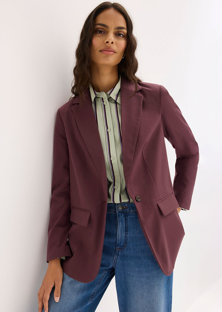 Ein stilvoller Look mit bordeauxfarbenem Blazer, gestreifter Bluse und blauen Jeans.