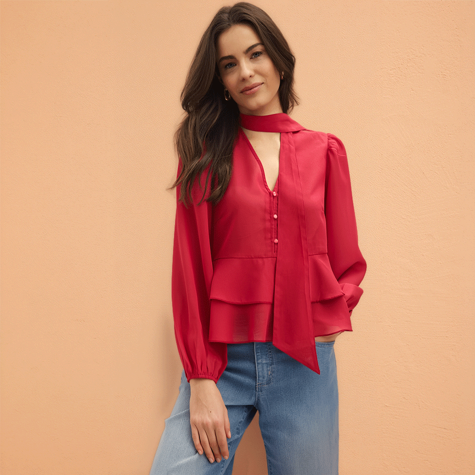 Auffällige rote Bluse mit Knöpfen und Schalkragen, kombiniert mit einer lässigen blauen Jeans.