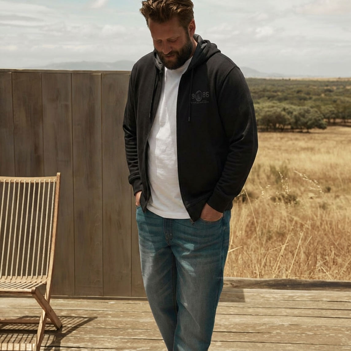 Schwarze Kapuzenjacke, weißes T-Shirt und bequeme blaue Jeans.