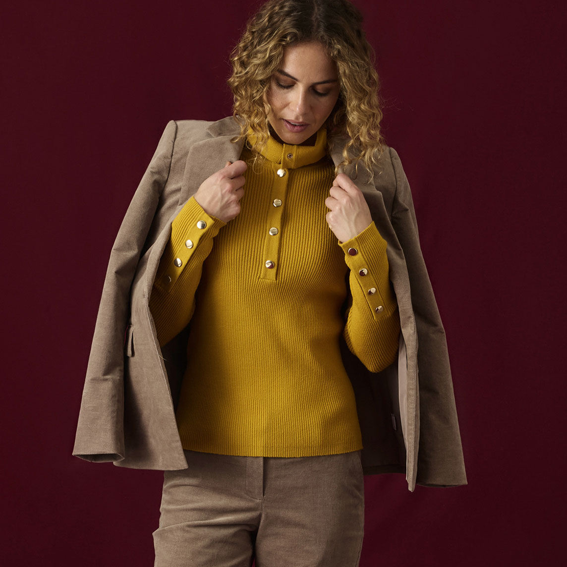 Gelber Rippstrickpullover mit Knöpfen, brauner Blazer, dazu eine Cordhose.