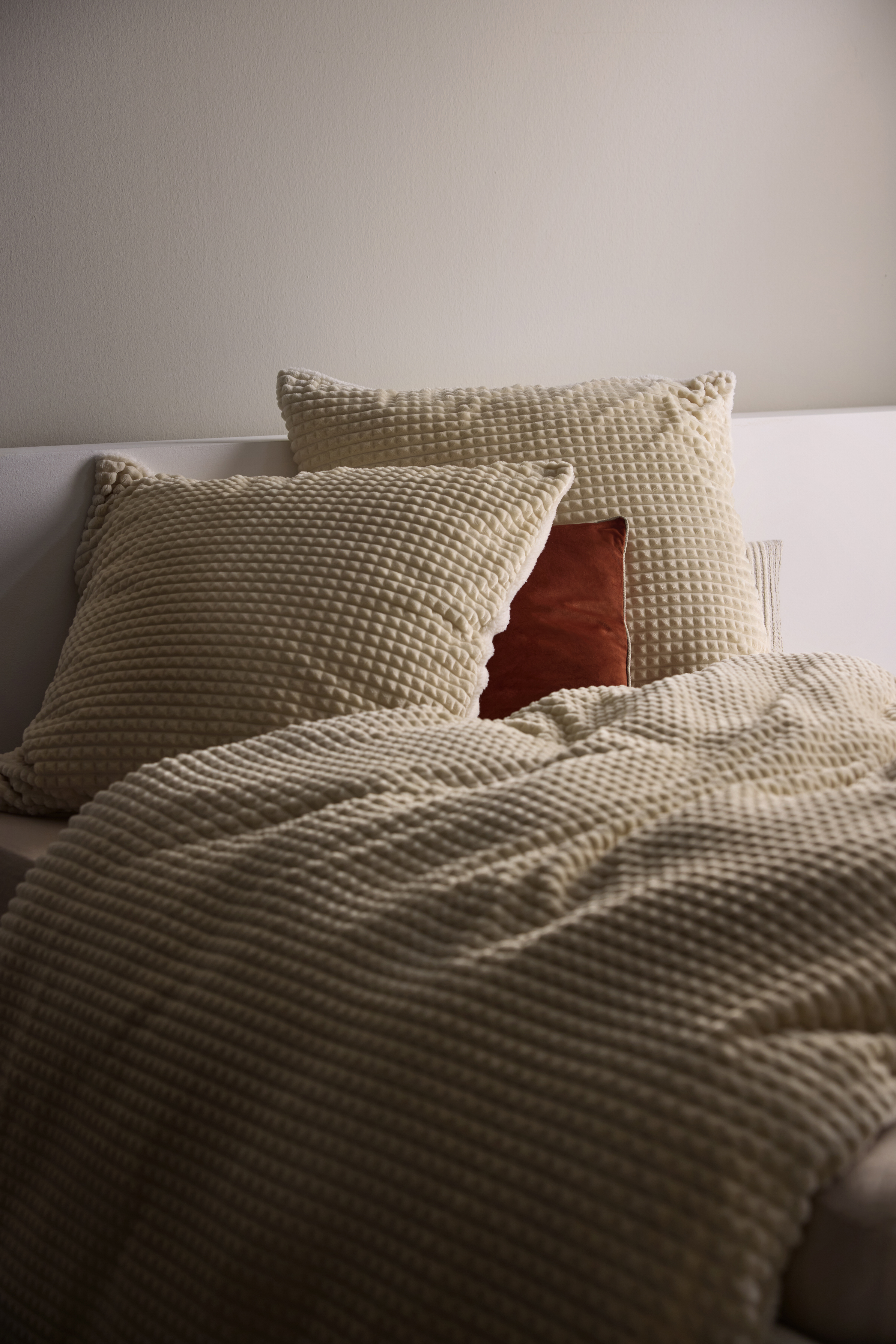 Strukturierte Stoffe in Cremetönen kleiden das Bett weich und gemütlich.