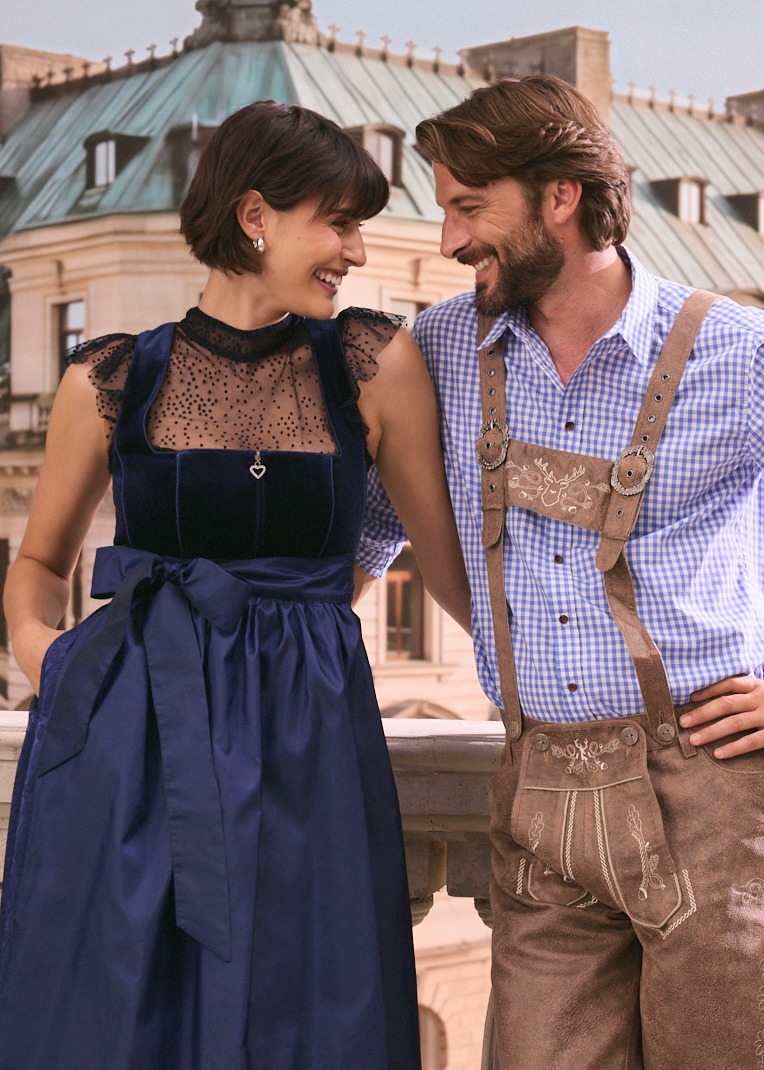 Elegantes dunkelblaues Dirndl trifft auf klassische Lederhosen und kariertes Hemd.