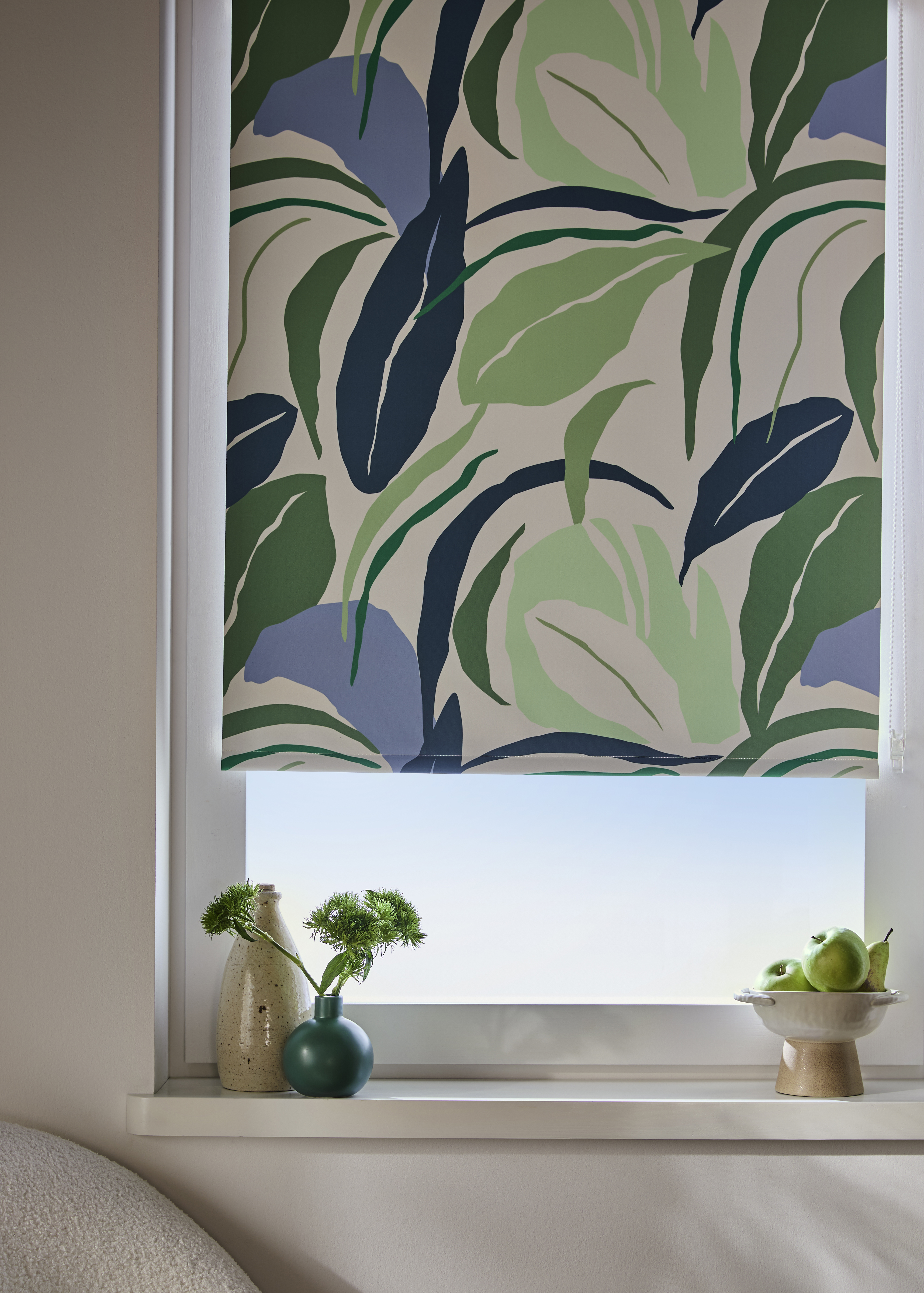 Stilvolles Rollo mit grün-blauem Blättermuster schmückt das helle Fenster im modernen Wohnraum.