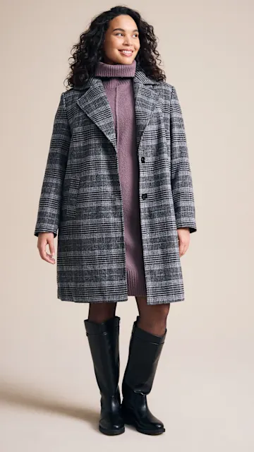 Lila Rollkragenkleid, karierter Mantel, schwarze Strumpfhose und Stiefel.