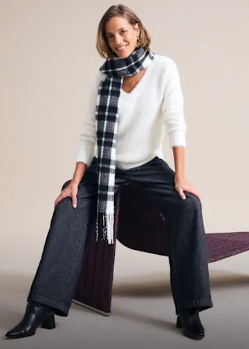 Weißer, flauschiger Pullover und dunkle Hose betonen den entspannten Stil.