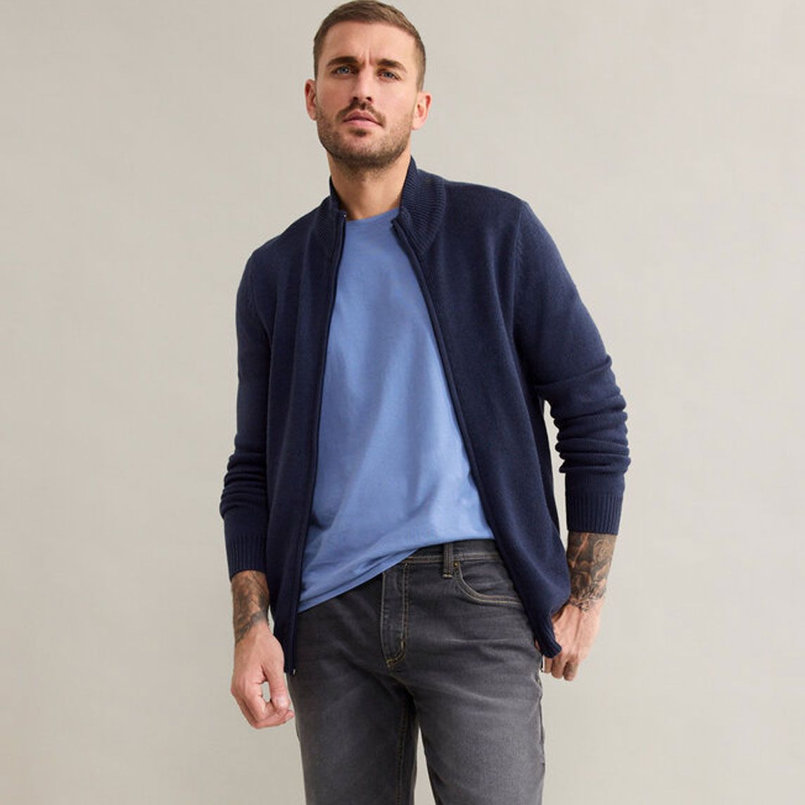 Eleganter Cardigan in Marineblau über hellblauem T-Shirt, kombiniert mit grauen Jeans. Lässiger Stil.