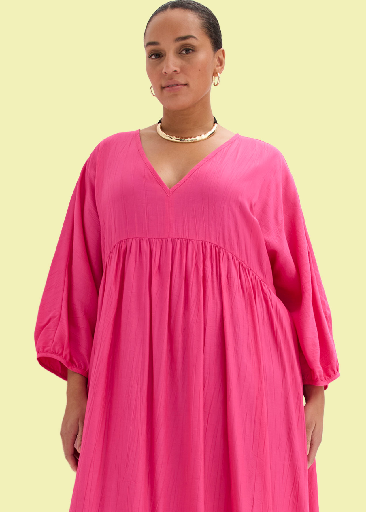 Pinkes Stufenkleid mit V-Ausschnitt und weiten Ärmeln.