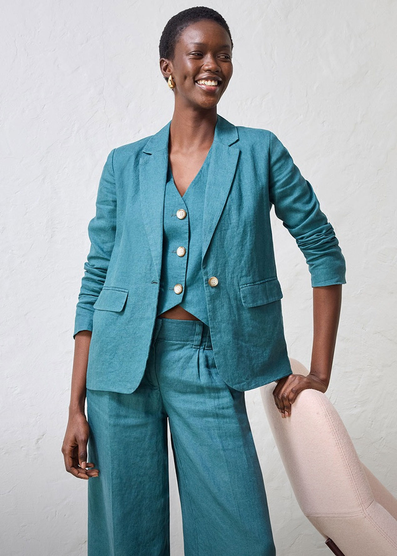 Eleganter türkisfarbener Anzug mit Blazer, Weste und weiter Hose. Goldene Knöpfe setzen Akzente.