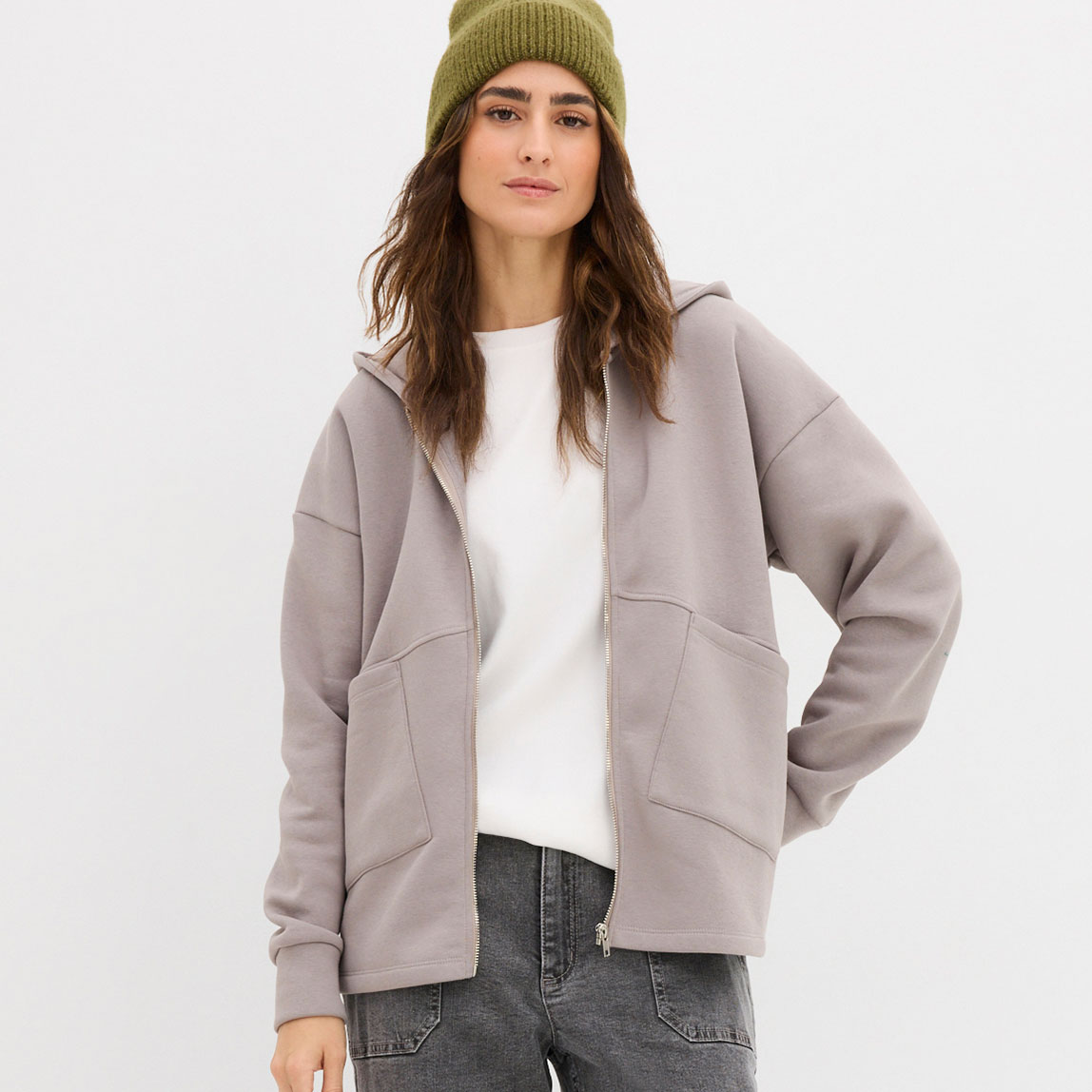 Weißes Shirt und graue Sweatjacke über grauer Jeans.