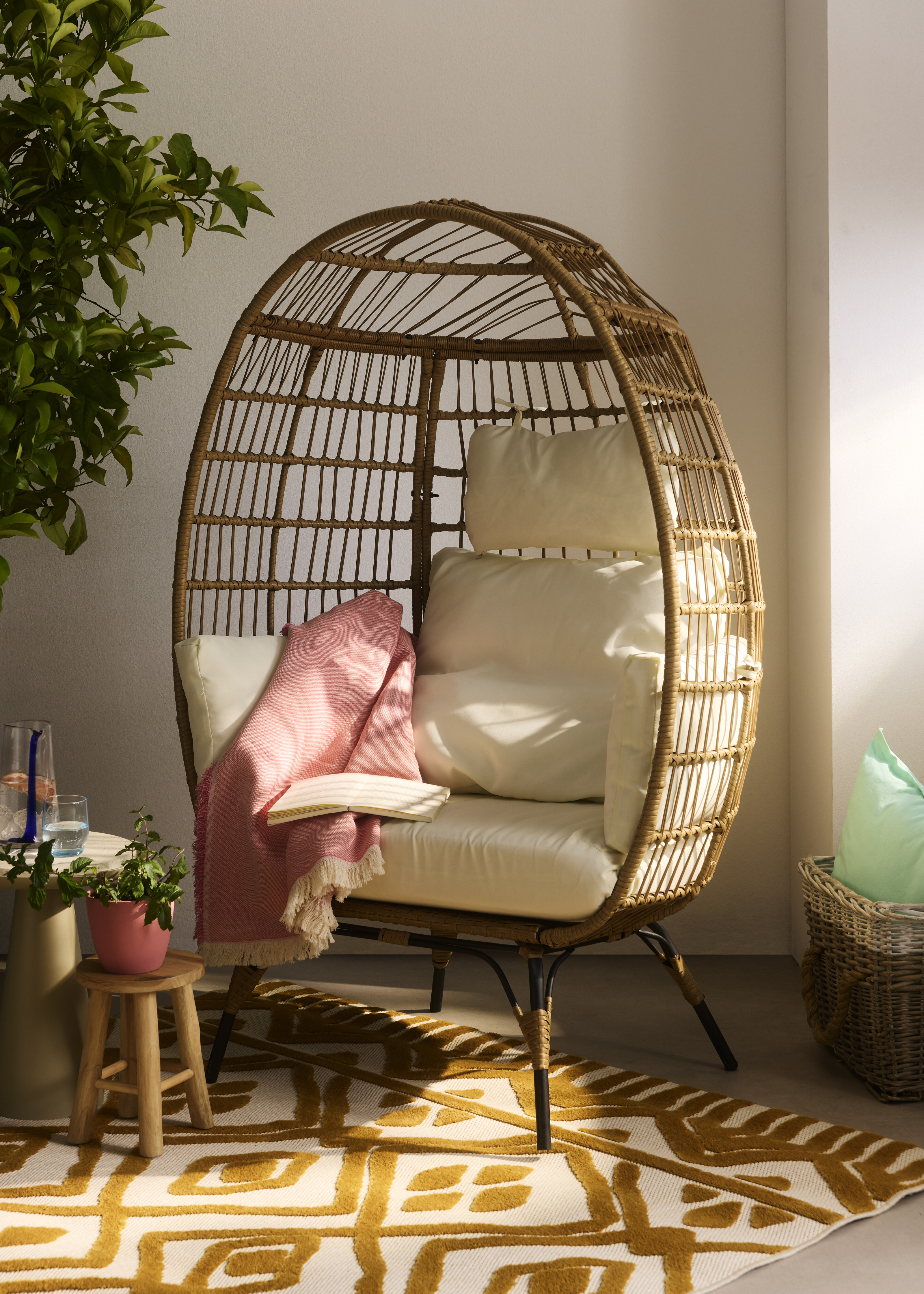 Rattansessel mit weichen, hellen Kissen.