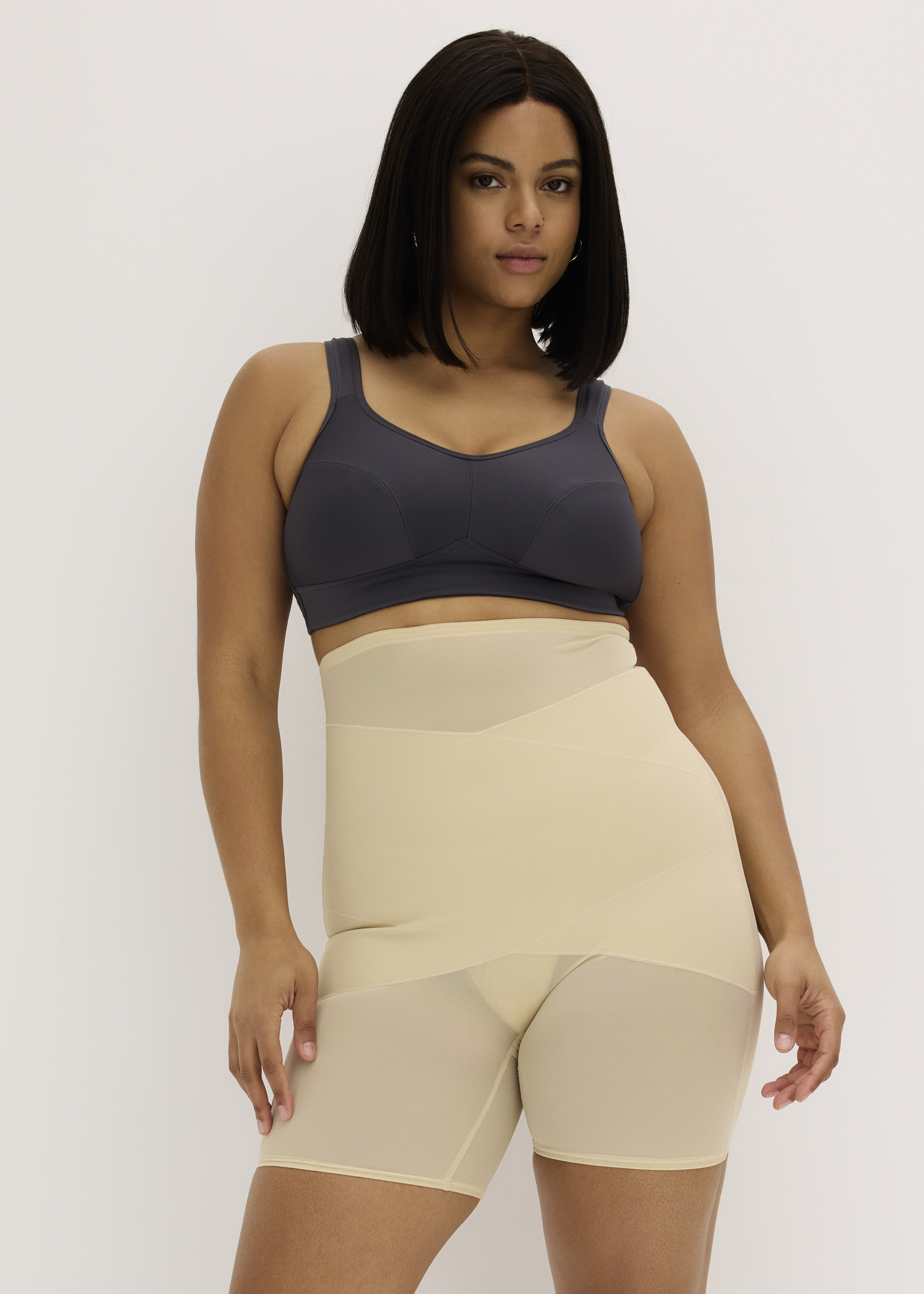 Dunkler BH und hautfarbene, figurformende Shapewear-Shorts.