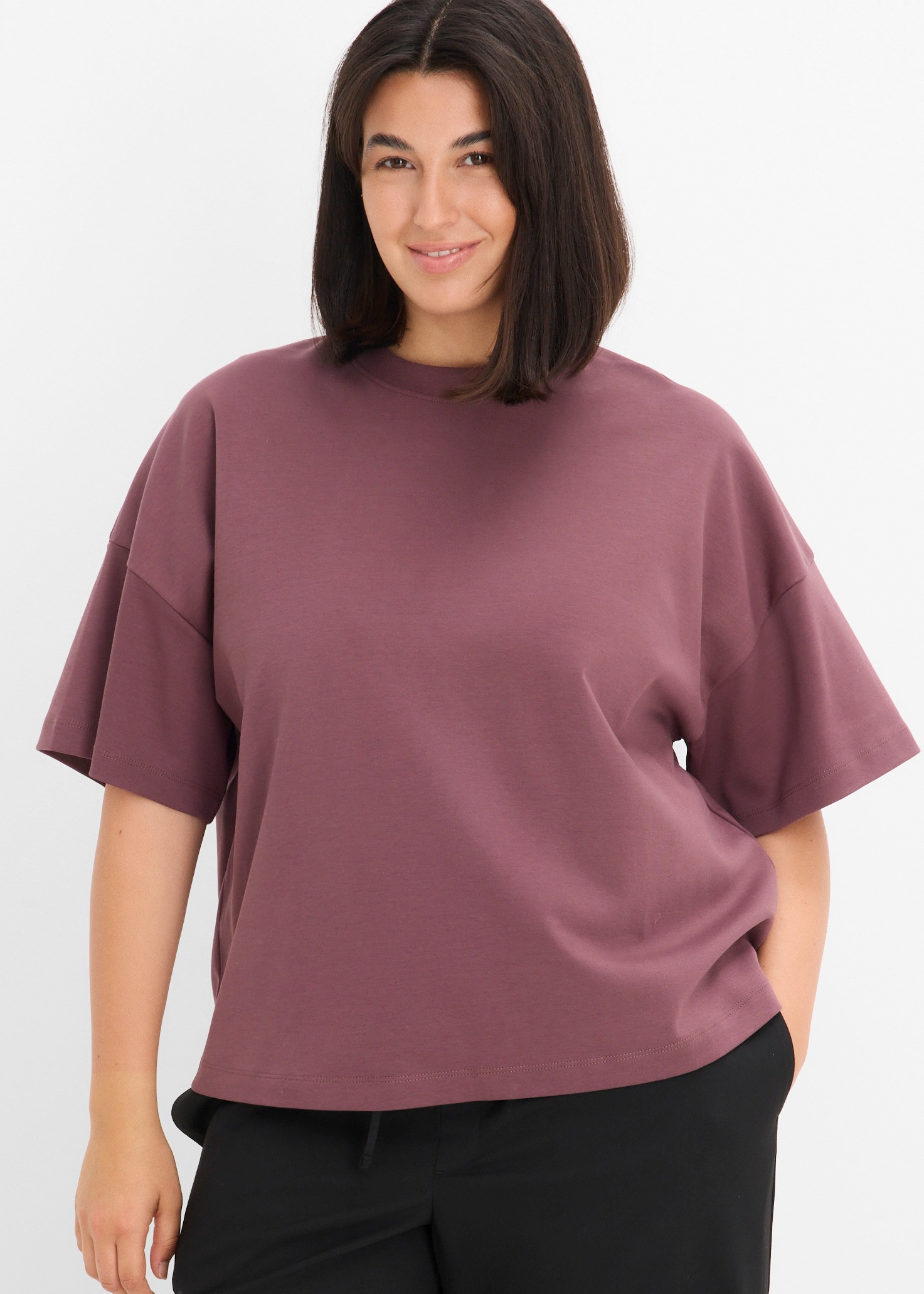 Bequemes pflaumenfarbenes Oversize-T-Shirt und schlichte schwarze Hose für einen lässigen Look.