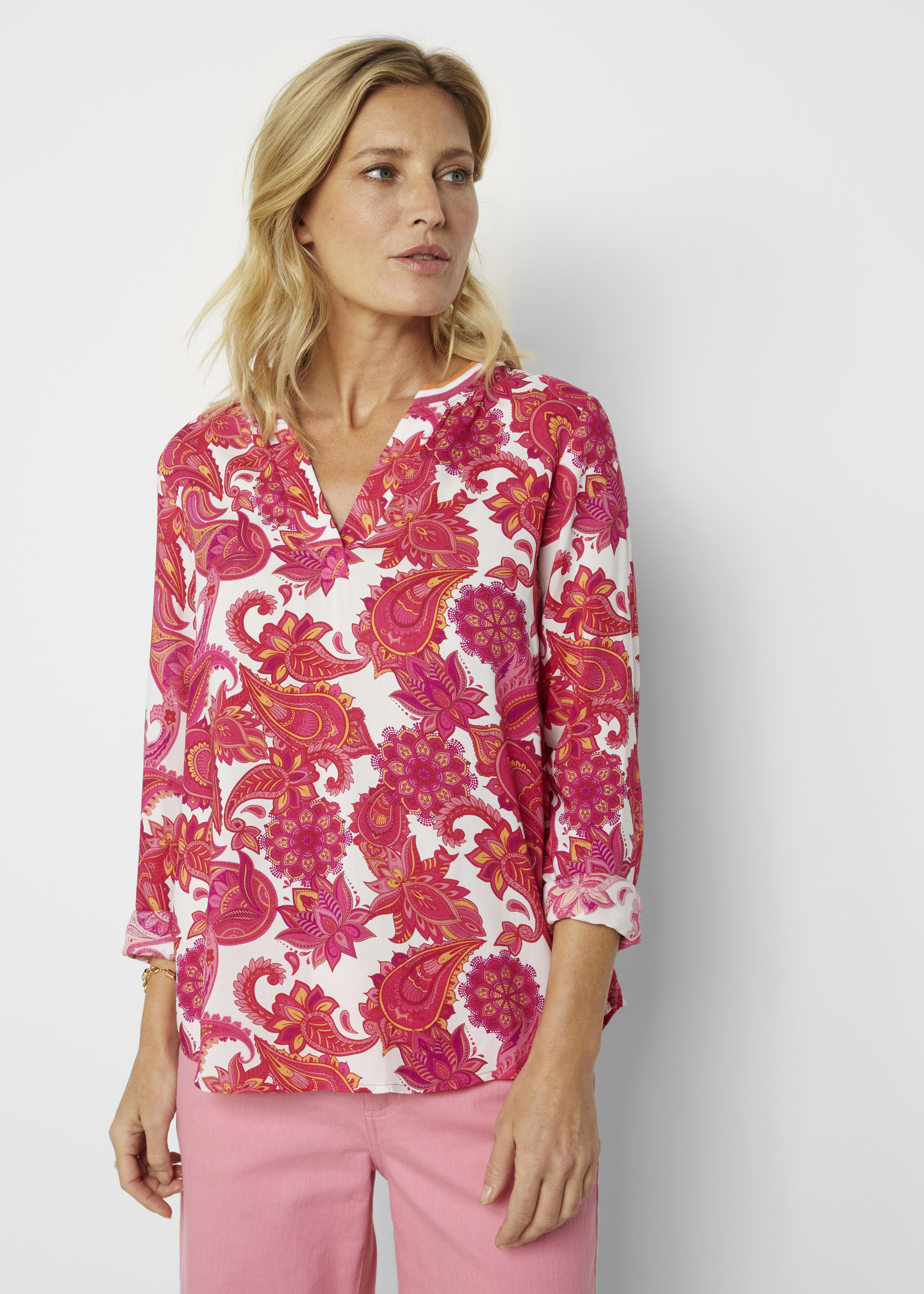 Trendige Bluse mit auffälligem pinkfarbenem Paisleymuster und passender rosa Hose.