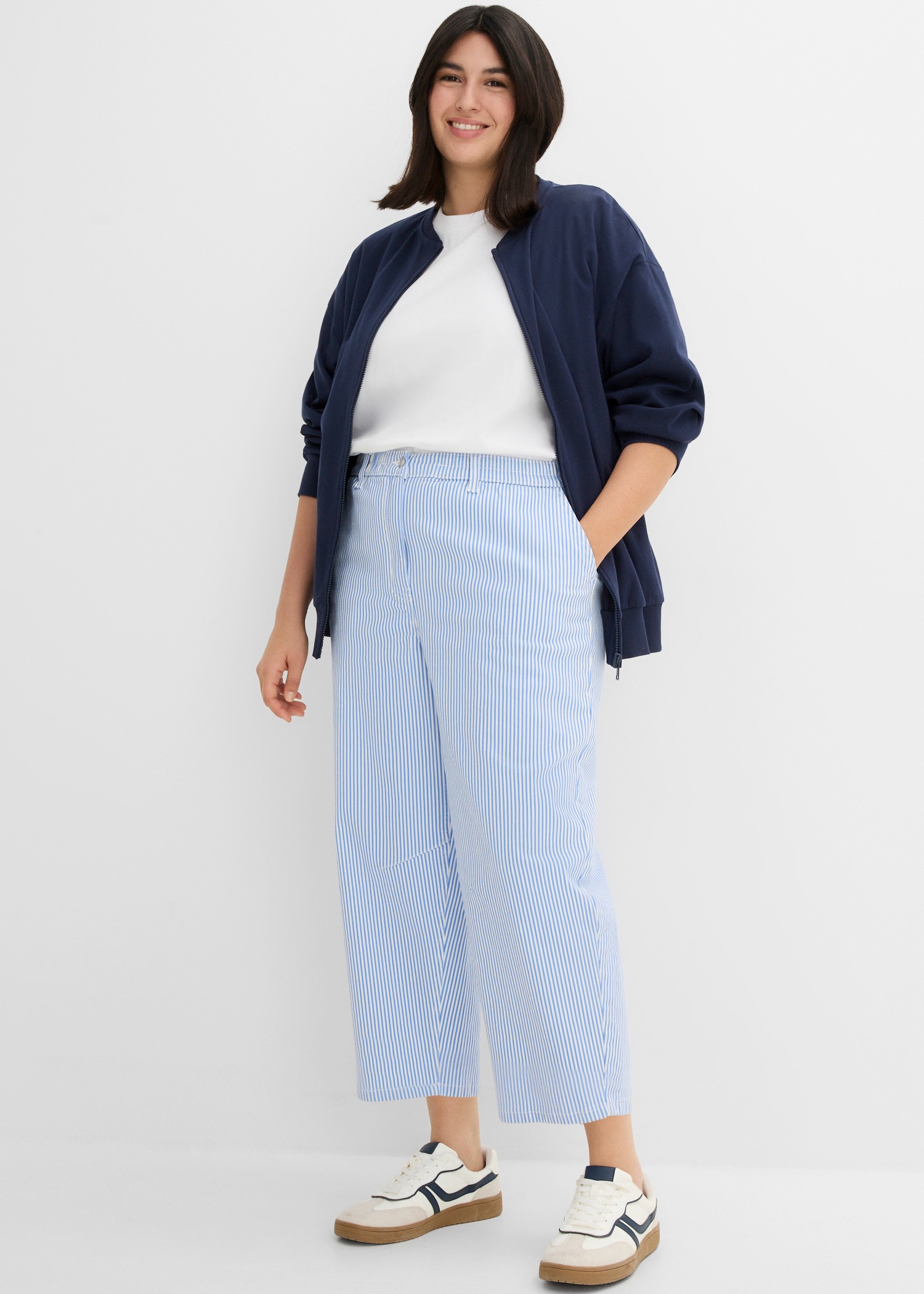 Blaue Jacke, weißes Shirt, hellblau gestreifte Hose und bequeme Sneaker.