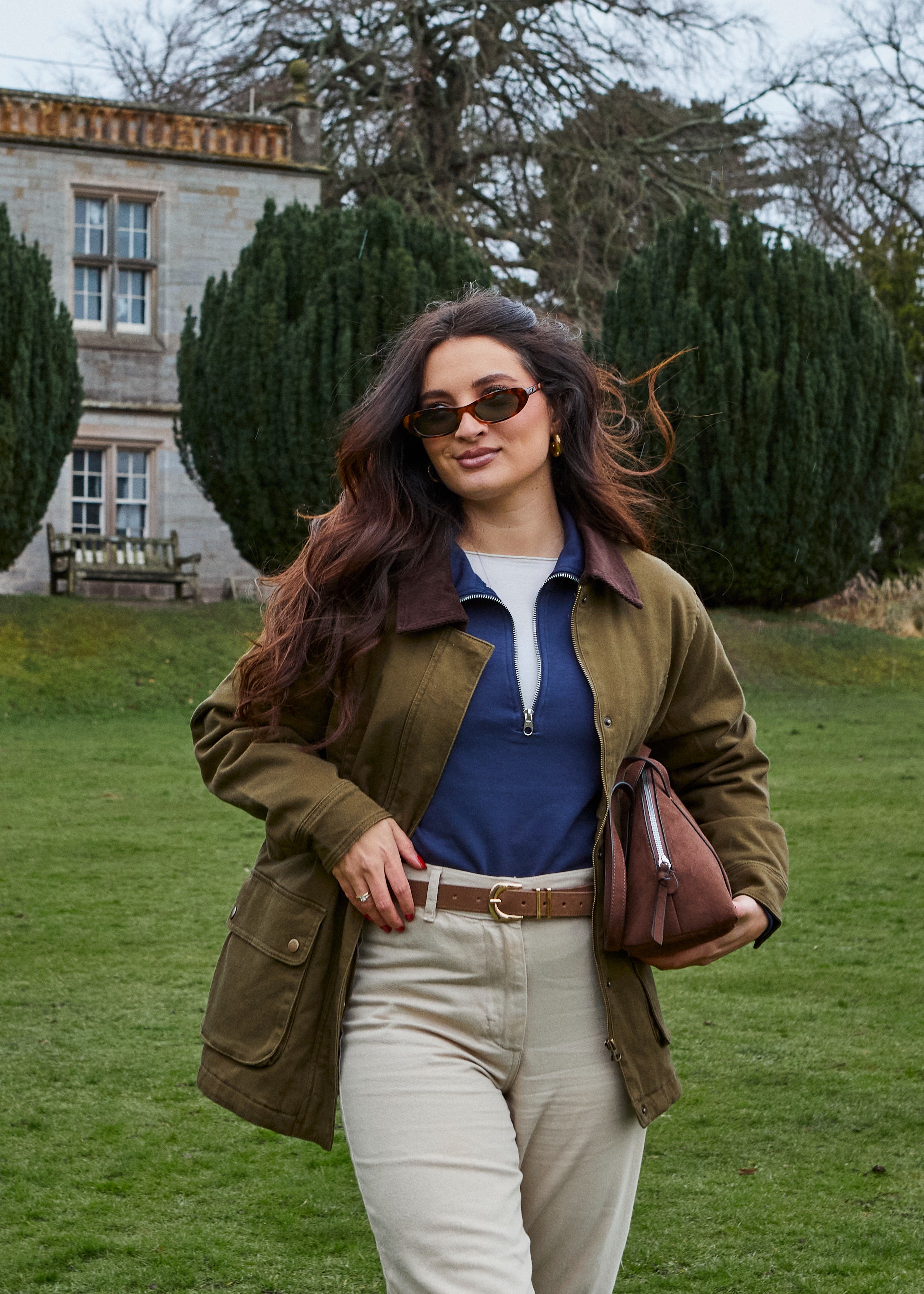 Olivgrüne Jacke, dunkelblaues Oberteil und helle Hose 