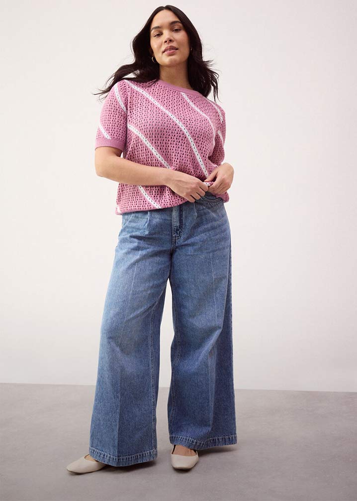 Lockerer Strickpullover in Rosa, kombiniert mit weit geschnittener Jeans.