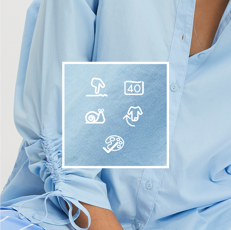 Hellblaues Hemd mit Pflegesymbolen auf dem Etikett. Lockere Passform und geknotete Ärmel.