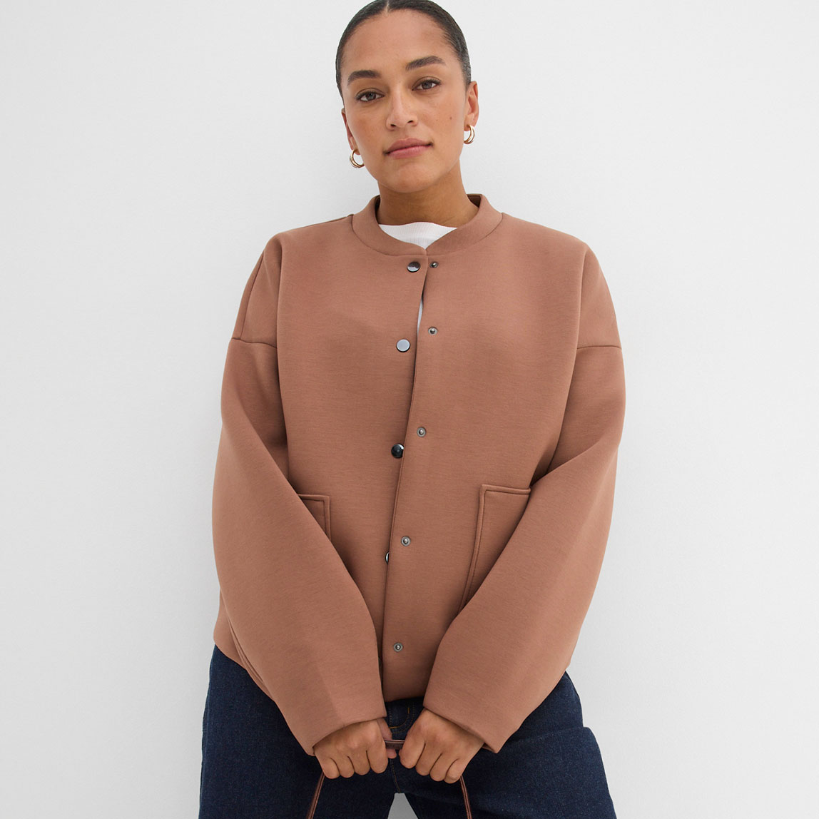 Jacke in Terrakotta mit Druckknöpfen und Rundhalsausschnitt.