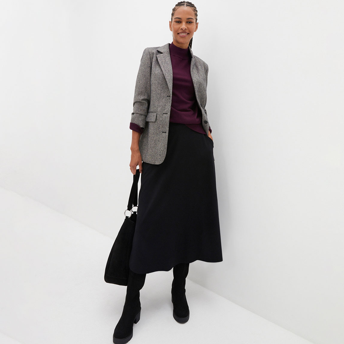 Karierter Blazer, violettes Oberteil und langer schwarzer Rock.