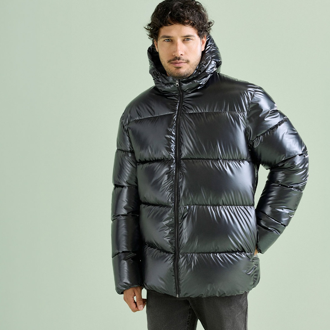 Glänzende, schwarze Daunenjacke mit Kapuze und dunkle Hose, ein lässiger Look.