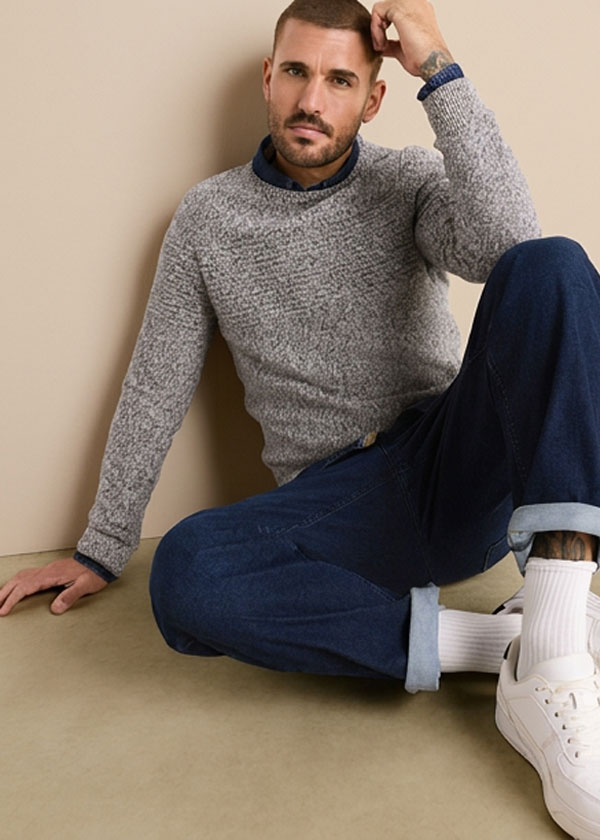 Grob gestrickter Pullover, Jeans mit Krempe, weiße Socken und helle Sneaker.