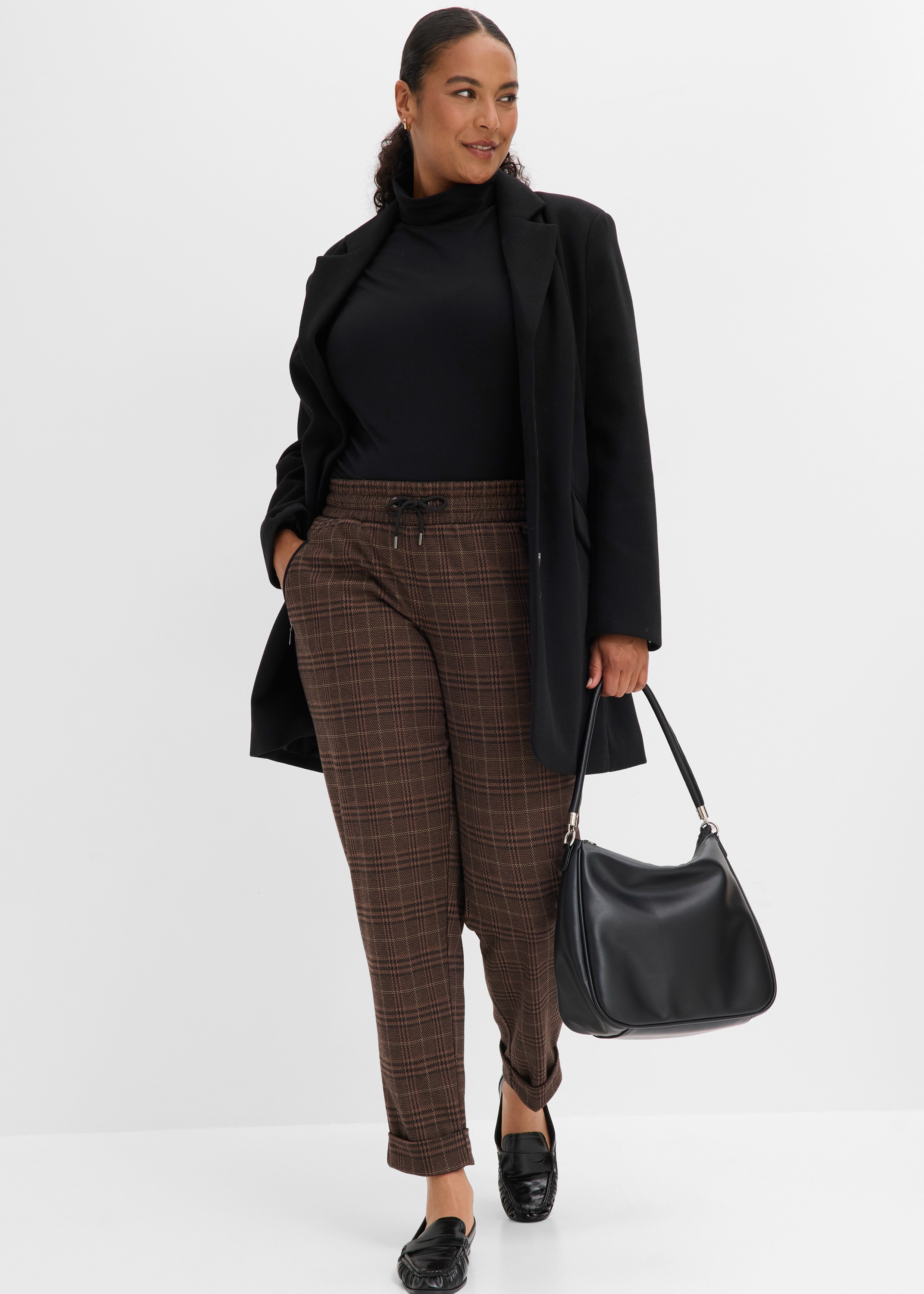 Schwarzer Rollkragen, langer Blazer, karierte Hose, elegante Schuhe und schwarze Tasche.