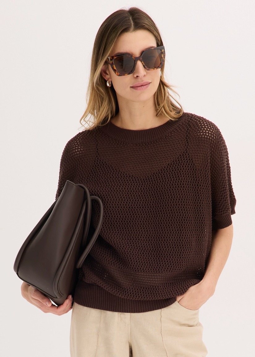 Brauner Lochstrickpullover, helle Leinenhose und eine elegante braune Tasche.