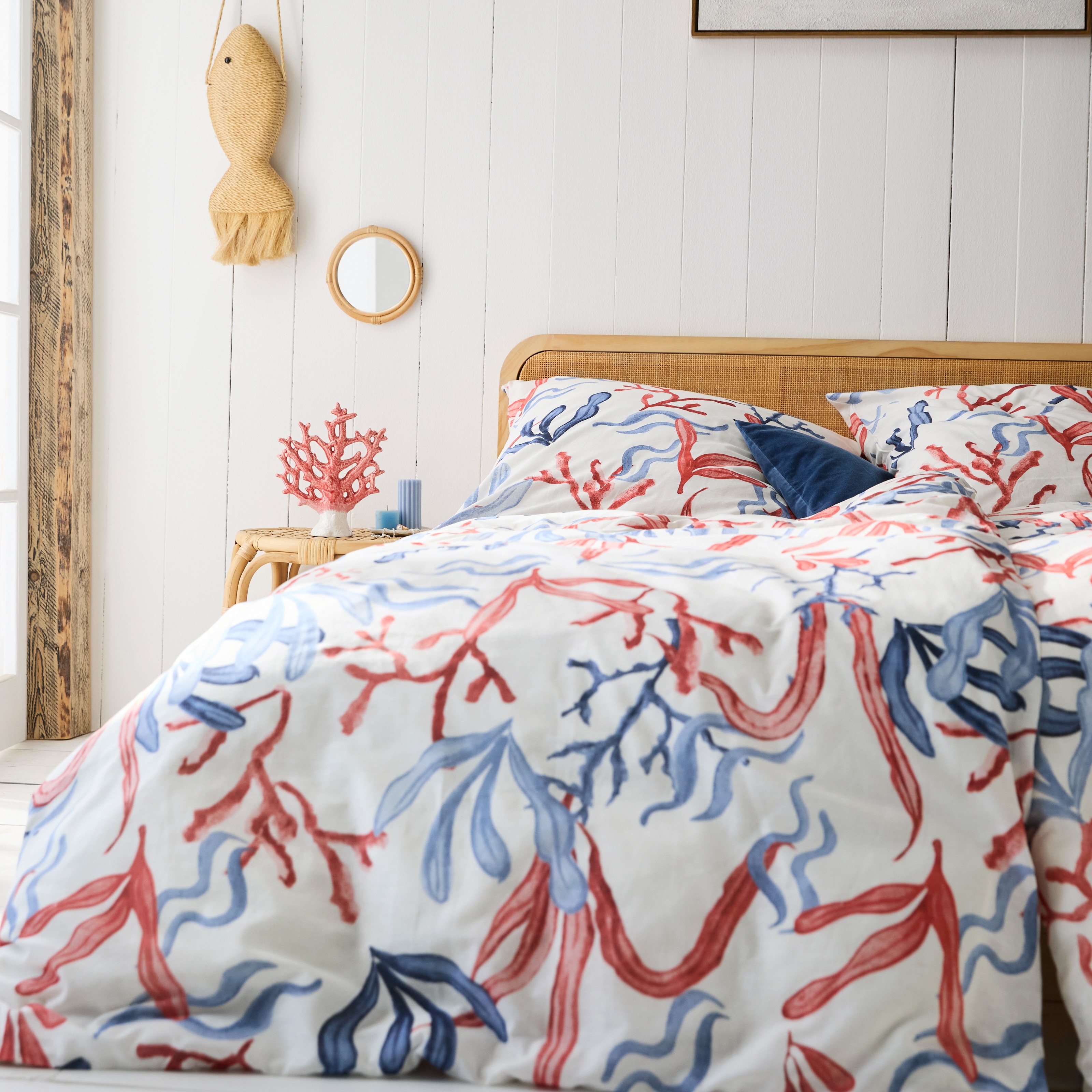 Gemusterte Bettwäsche mit rot-blauen Korallenmotiven geschmückt im maritimen Stil.