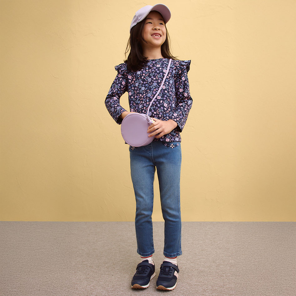 Blumige Bluse mit Rüschen dazu Jeans und Sneakers. 